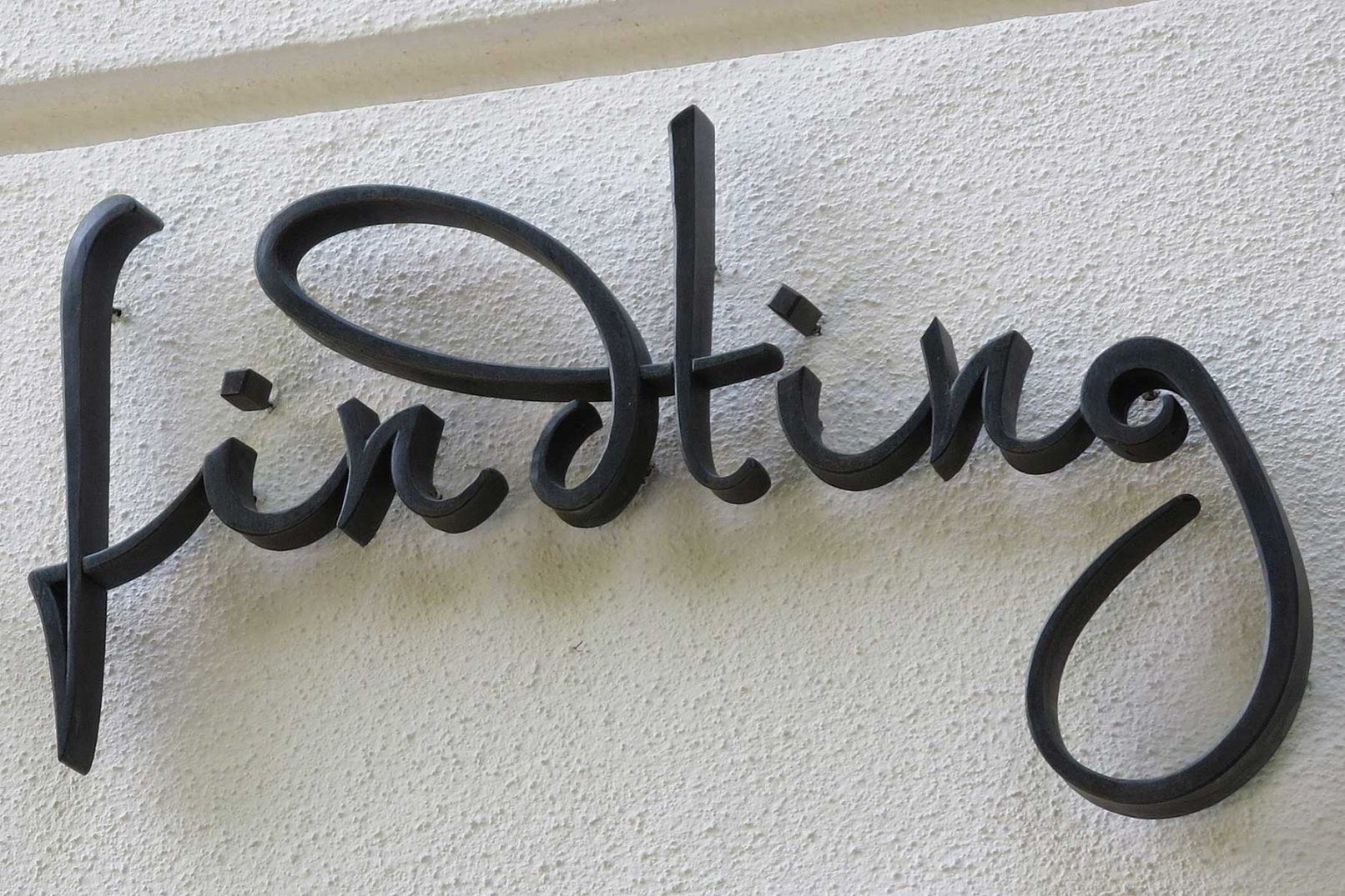 Seitenansicht geschwungener Schriftzug aus Bronze