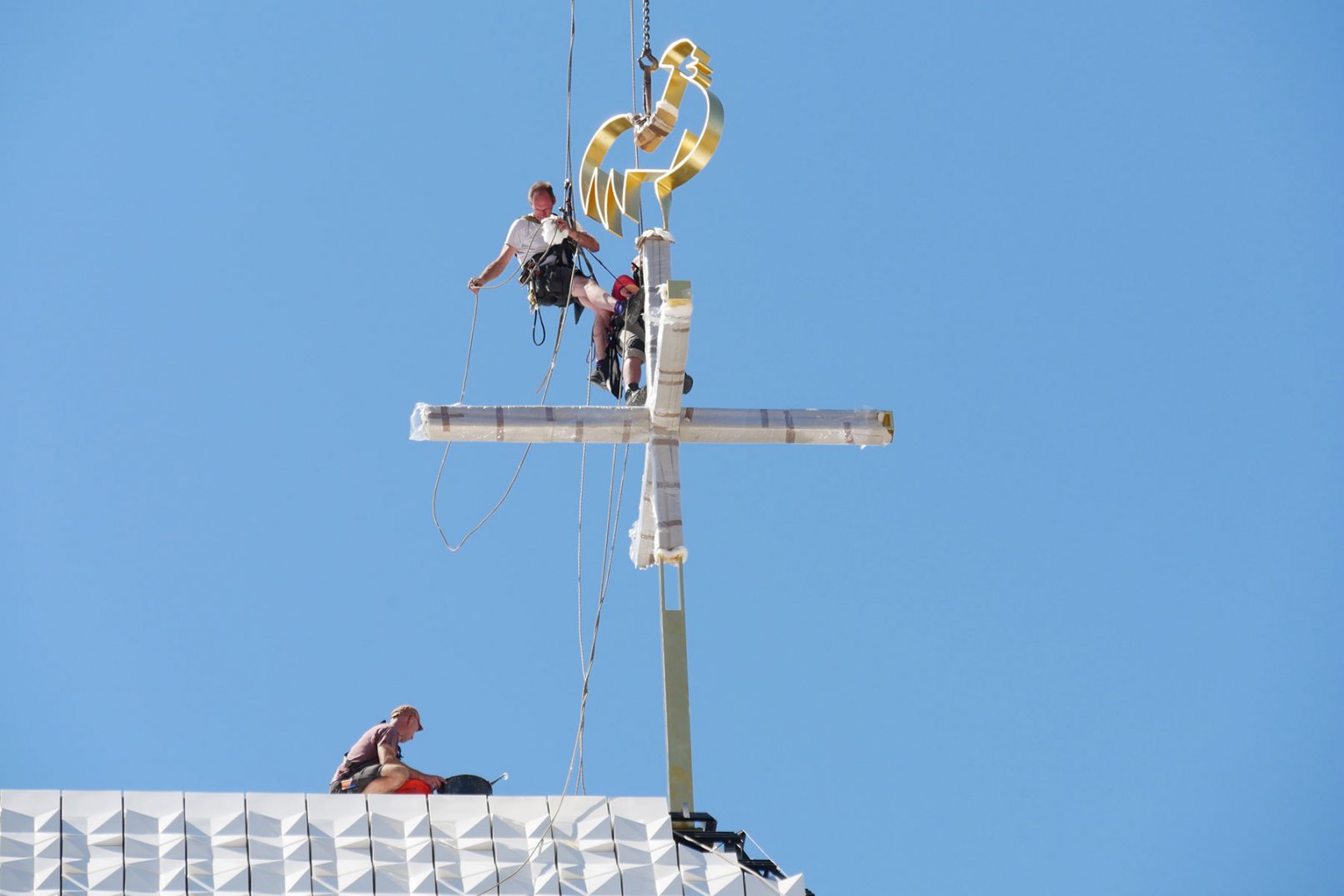 Montage des vergoldeten Turmkreuzes azuf dem Dach des Kirchenzentrum Seliger Pater Rupert Mayer