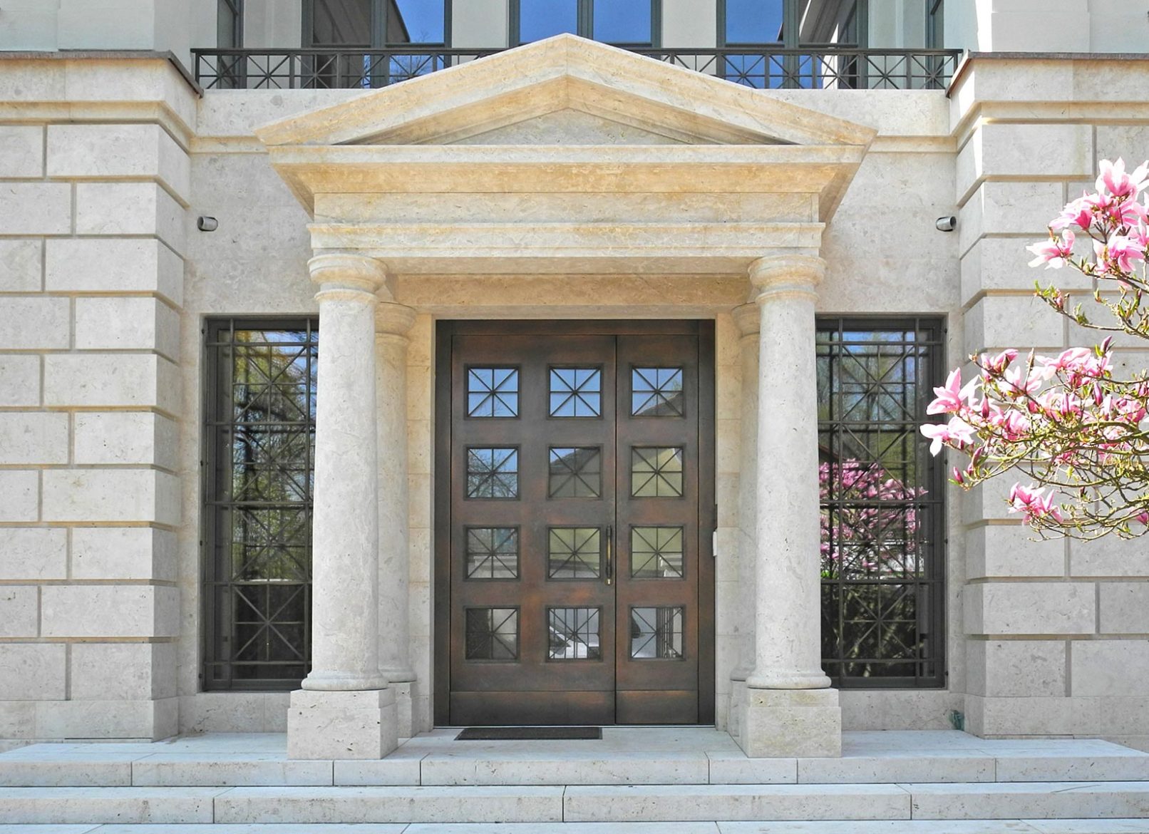 Eingangsportal mit Bronzeblech verkleidet und seitlichen Fenstergittern.